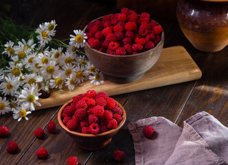 Fresh raspberries in a clay and wooden bowl on a dark wooden table
