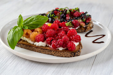 Sandwiches with cream cheese and berries combined with basil. Summer snack for breakfast or snack.