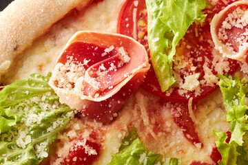 Pizza with prosciutto, lettuce salad and parmesan.
