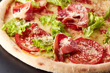Pizza with prosciutto, lettuce salad and parmesan.