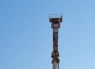 Close-up of a yellow tower crane  against a clear blue sky