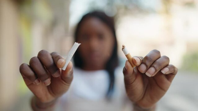 Young african american woman breaking cigarette at street