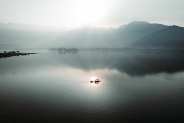 Beautiful view of a lake with hills and mountains in the background on a foggy day