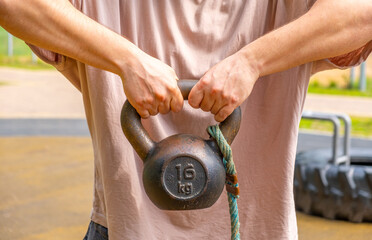 An athlete on the street is engaged with a weight of 16 kilograms. Doing sports on the street.