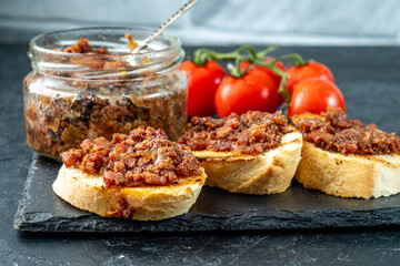 Bacon jam on fried baguette slices. Bacon snack. Close-up.