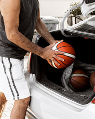 Close-up image of basketball coach puts the balls in the trunk of his car going to workout.