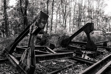 Grayscale shot of abandoned broken metalworks on a railroad