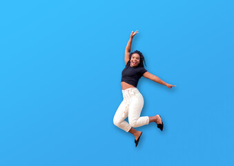 Fototapeta na wymiar Happy black woman jumping over isolated blue wall