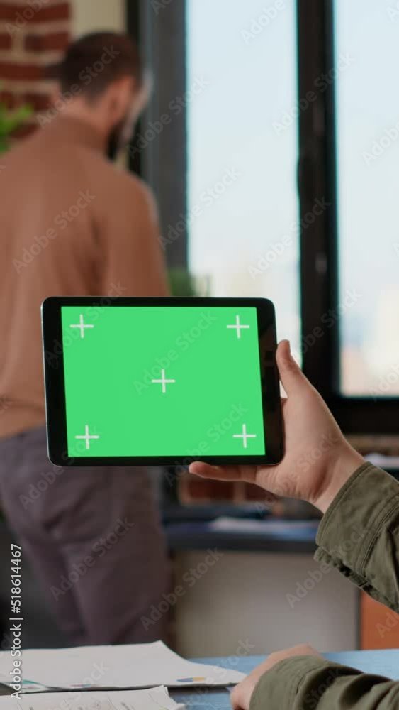 Poster vertical video: office worker analyzing horizontal greenscreen on tablet, looking at blank copyspace