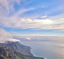 Panorama of a calm ocean and mountains with a cloudy blue cloudy sky background and copy space. Stunning nature landscape of the sea and horizon against The twelve apostles landmark in Cape Town