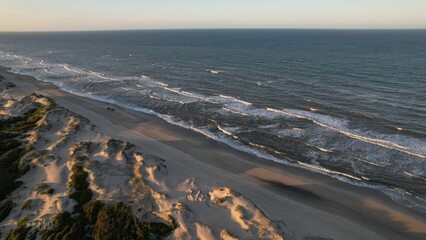 Aerial view of sea waves crashing into the sandy beach of Outer Banks island North Carolina