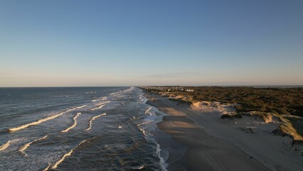 Aerial view of sea waves crashing into the sandy beach of Outer Banks island North Carolina