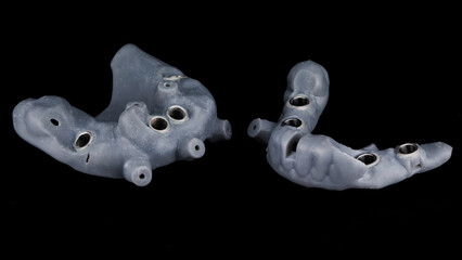 two gray surgical dental templates for total implantation on a black background