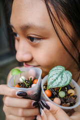 Closeup of Pretty Asian Teen Girl Holding Baby Tropical Plants