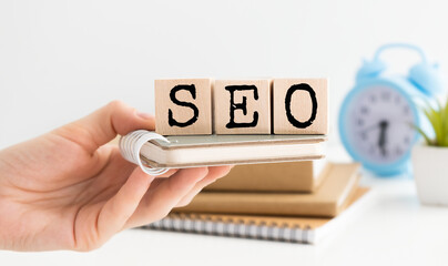 Close-up of businessman collecting words seo with wooden cubes. Search engine optimization concept