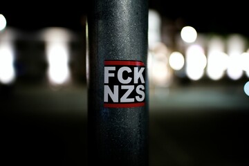 Close-up shot of the FCK NZS popular anti-nazi acronym posted on a street pole - obrazy, fototapety, plakaty