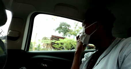 African man in taxi using cellphone device listening to audio message during pandemic