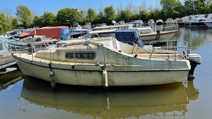 Dirty old yachts near the lakeshore with lush green trees in the background