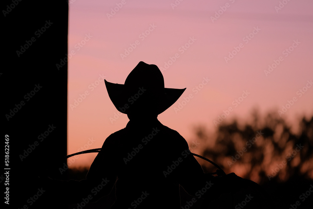 Wall mural young kid cowboy in texas with sunset background for western industry concept.