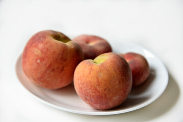 Juicy red and yellow peaches on a white plate. Delicious peaches for lunch.