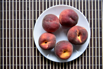 Juicy red and yellow peaches on a white plate. Delicious peaches for lunch.