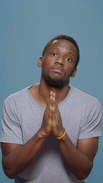 Vertical video: Hopeful man doign prayer gesture with hands in front of camera, begging and imploring for trust and fortune. Wishful person praying and asking for forgiveness, please and apologize