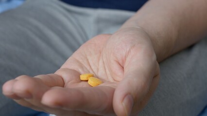 Close-up view of the palm into which two pills are poured and taken. Tablets in the hand of a...