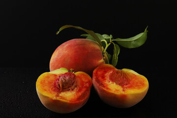 Fototapeta na wymiar Ripe peaches in a cut with a branch under dark lighting. Close-up