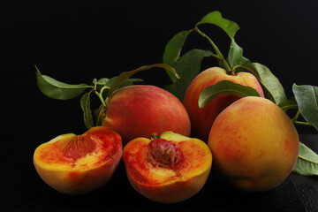 Ripe peaches in a cut with a branch under dark lighting. Close-up