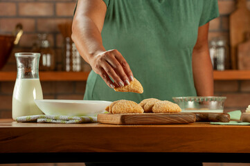Woman breading brazilian meat stuffed croquette (risolis de carne) on a wooden table. Top view.