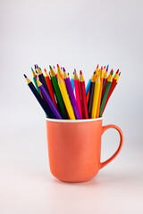 A group of color pencils in a pink cup on an isolated  white background