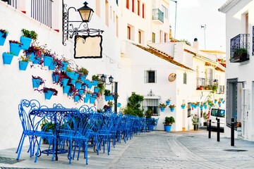 Row of blue cafe tables and chairs with potted plants in the town of Mijas Pueblo Blanco, Spain