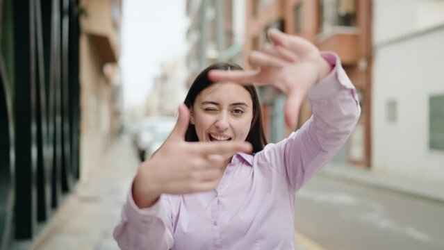 Young hispanic woman smiling confident doing photo gesture with hands at street