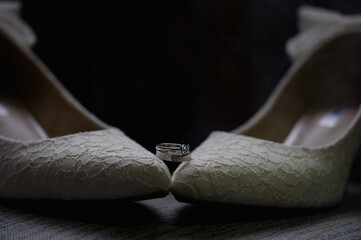 wedding ring on white bride's shoes on black background.concept for wedding day and ceremony