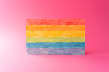 LGTBIQ+ pride flag made of handmade paper on a pink or fuchsia background
