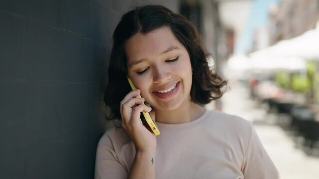 Young woman smiling confident talking on the smartphone at street