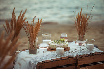 picnic in the evening at sunset on the sandy shore of the sea or ocean. decor in boho and rustic style. © Daria