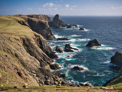 Dramatic coastal cliff scenery on the Ness of Hillswick, Northmavine, in the UNESCO Global Geopark of Shetland, UK - taken on a sunny day showing the clear, blue water of the Islands in the North Sea.