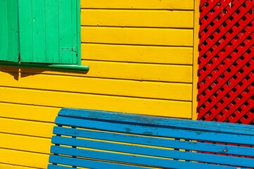 Blue wooden bench in front of a colorful house's outer wall in La Boca, Buenos Aires, Argentina