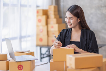 Obraz na płótnie Canvas Portrait of young Asian woman SME working with a box at home the workplace.start-up small business owner, small business entrepreneur SME or freelance business online and delivery concept.