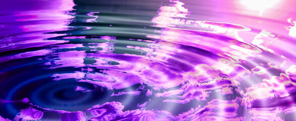 An artificially created abstract rippled pink world with a reflection of the sky, clouds, and sun. Empty puddle purple water or liquid creating waves while reflecting nature outside after rain
