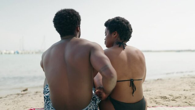 African american man and woman couple wearing swimsuit hugging each other at seaside