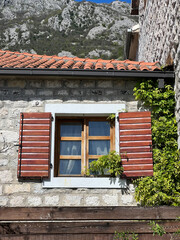 Wooden window with shutters on the stone facade of the house