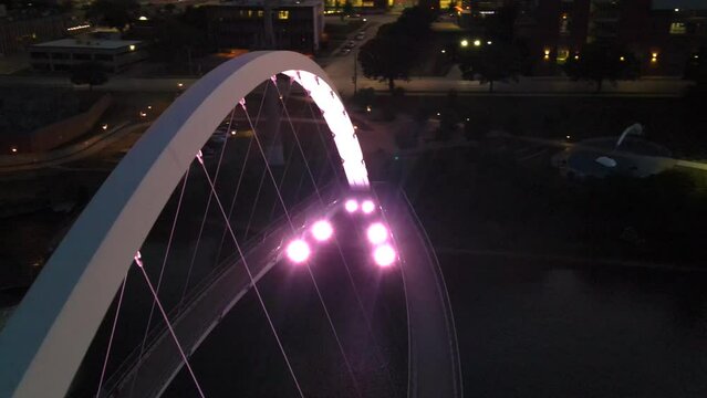 Aerial drone orbit of Center Street Bridge with lights over Des Moines River in downtown Des Moines, Iowa at night in summer