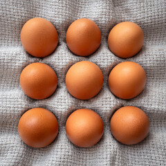 group of  brown chicken eggs on a grey table linen cloth, view from above