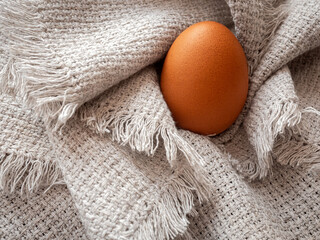 Obraz na płótnie Canvas Brown chicken egg on a white table linen cloth
