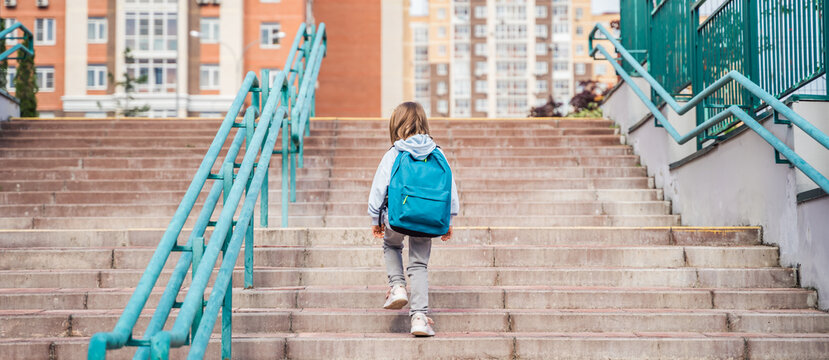 Back to elementary, primary school. Little girl with big backpack goes in hurry, late to first grade alone in autumn morning. Education, future of children. Happy, unhappy pupil kid on stair steps