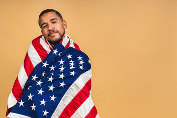 Portrait of positive african american black guy holding usa flag, isolated over beige background.