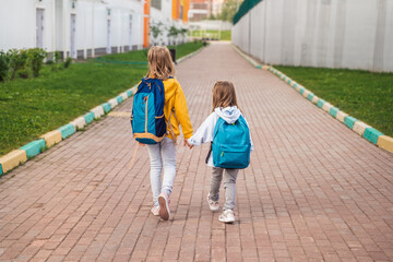 Back to elementary,primary school.Little girls,sisters with big backpack go in hurry,late to first grade alone in autumn morning.Education,future of children.Happy,unhappy pupils kids walk themselves