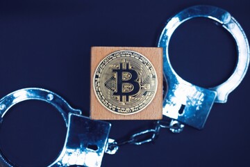 The bitcoin in the center with handcuffs as background . Concept of illegal .